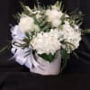 WHITE HYDRANGEA, ROSES, TULIPS AND ASSORTED GREENS IN A WHITE CONTAINER
