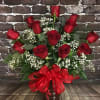 A beautiful dozen red roses adorned with filler and greenery in a