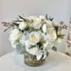 A beautiful arrangement of ivory roses, white hydrangea, and white ranunculus sway