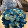 Stitch azul con 35 rosas azules en una caja de cilindro representa