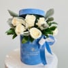 This charming arrangement features creamy white roses nestled in a soft sky-blue