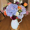 A stunning blend of elegance and charm, this hand-arranged floral display features