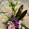 Pink lilies, purple orchids and spray roses with beautiful leaves arranged in