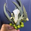 A refined boutonniere featuring a carefully selected bloom with subtle greenery, designed