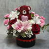 A charming Valentine arrangement featuring a sparkling red teddy bear nestled among