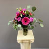 Bright pink, lavender, and purple flowers gathered in a glass vase. Just