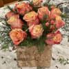 This elegant arrangement of vibrant orange roses and lush greenery is perfect