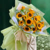 Bright sunflower bouquet featuring fresh sunflowers, soft greenery, and seasonal accents, wrapped