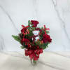 Red roses are arranged with fresh pine and Christmas fern, accented by