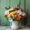 A cheery arrangement designed in a keepsake white pitcher full of roses