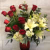 A classic floral arrangement displayed in a red glass vase. It features