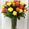 A vibrant display of yellow and orange roses arranged in a tall