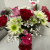 Floral arrangement with different flowers in a glass container and ribbon, a