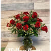 18 red roses in a vase with filler and greens
