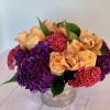 Vibrant, tight floral arrangement of dutch varieties in deep purple, fuschia, green
