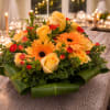 A warm and cheerful floral arrangement featuring golden yellow roses, vibrant orange