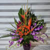 A ONE-SIDED 32INS TALL TROPICAL ARRANGEMENT CONSISTING OF RED HELICONIA FLOWERS, ORANGE