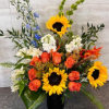 A bold, cheerful arrangement featuring **bright sunflowers**, **orange roses**, and **white accent