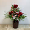 This romantic arrangement features rich red roses rising gracefully from a bed