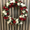 Red and white flowers styled in a wreath for funeral service