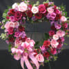 This open heart wreath is overflowing with roses in shades of pink