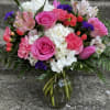This arrangement has roses, hydrangeas, tulips, carnations, alstroemeria, Hypericum, status, eucalyptus, and