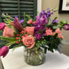 A bold arrangement of jewel toned flowers made in a low glass