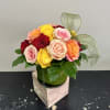 A dozen assorted roses in a modern styled shorter vase with greenery