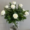 A dozen long stem white roses with assorted greenery in a clear