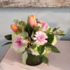 Delicate pastel colored spring blooms in a low cylinder vase.