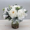 This beautiful white peony arrangement in a glass vase exudes elegance and