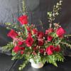 This arrangement has red roses, pray roses, wax flower and greenery 