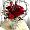 Two red roses, greens, and a tin-can wrapped in silver shiny wrap