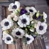 This exquisite arrangement features striking anemones alongside lush textures of eucalyptus and