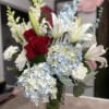 A collection of red roses, blooming white lilies, white carnations, white stock