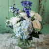 Blue and white flowers arranged in a clear cylinder vase. Approximately 14"