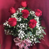 A lovely half dozen red roses arranged with greens and babies breath.
