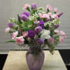 A variety of purple and pink flowers, such as carnations, lisianthus, roses