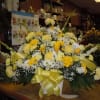 A mixture of white and yellow daisies, yellow carnations, yellow roses, yellow