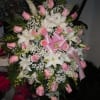 A mixture of pink roses, white lilies, pink llarkspur, baby's breath, greens