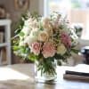 A soft, romantic cottage-style arrangement designed in a clear glass vase and