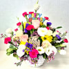 An assortment of white and colorful flowers arranged in a white basket