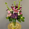 A tall glass vase of vibrant blooms including Stargazer Lilies, Bells of