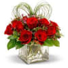 A clear glass cube vase with 12 red roses adorned by a