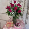 A dozen red roses in a clear glass vase accompanied by 6