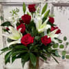 One dozen long stem red roses accompanied by white lilies and other