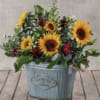 Oval galvanized tin overflowing with greens, sunflowers, carnations and fillers. Deluxe and