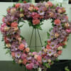 An open heart with a mixture of lavender daisies, pink carnations, pink