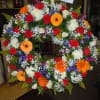 An open wreath with a mixture of gerbera daisies, roses, fuji mums