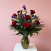 A striking Valentine arrangement featuring deep red roses paired with rich purple
